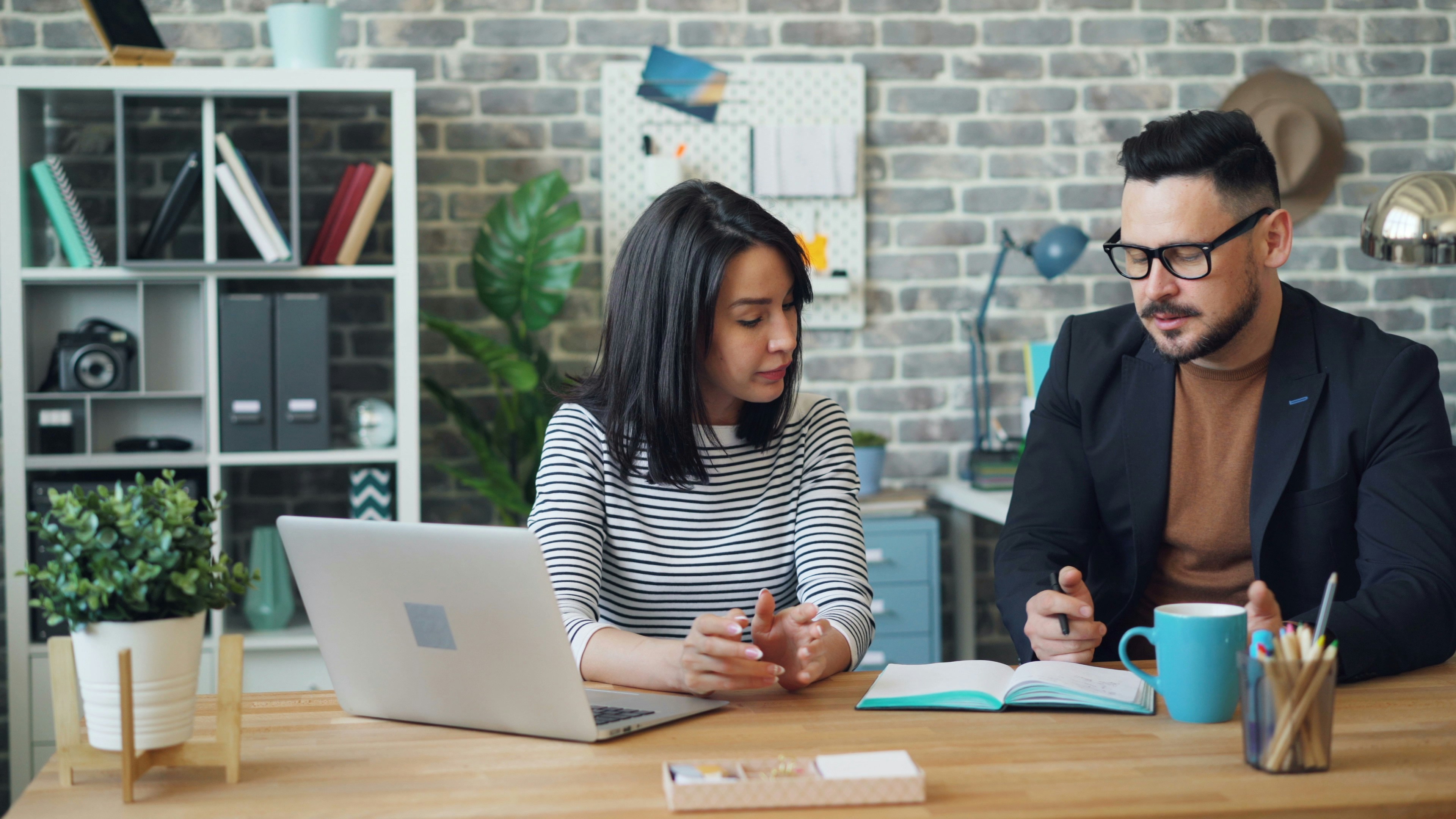 Two people sitting at a desk with a laptop